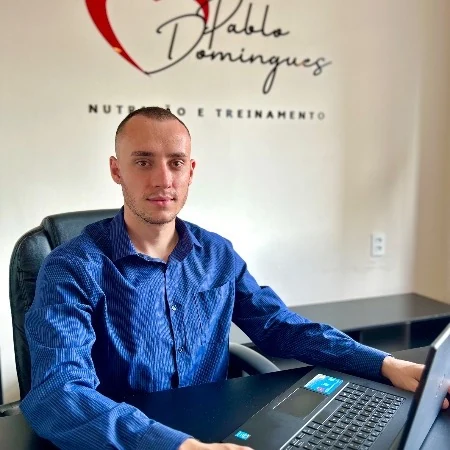 Pablo Domingues atendendo no consultório, com a logo Nutrição e Treinamento ao fundo